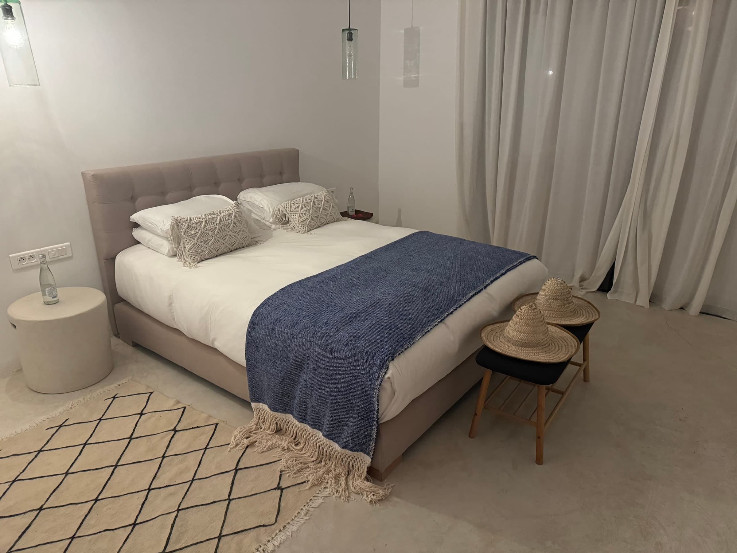 Le lit queen size de la chambre 3, banc et tapis berbère